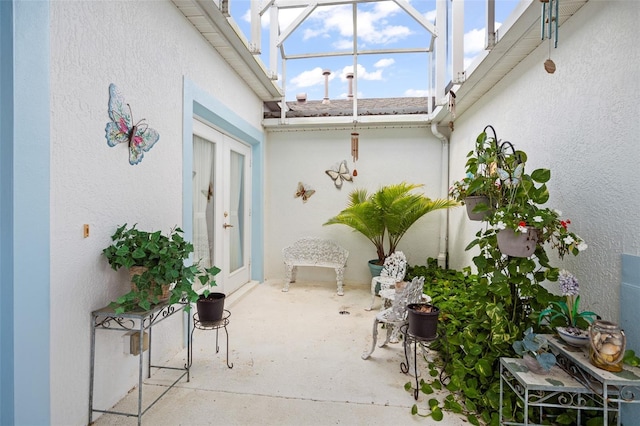 view of patio featuring french doors and glass enclosure