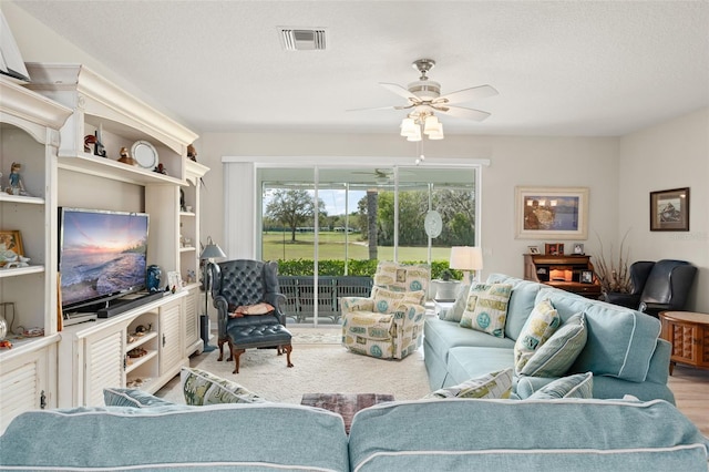 living area featuring a textured ceiling, visible vents, and ceiling fan