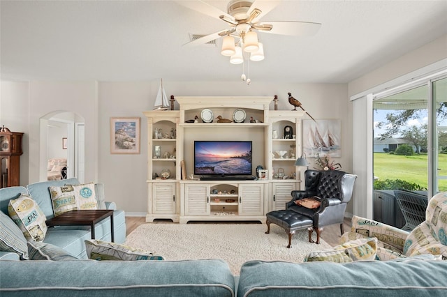 living room with baseboards, wood finished floors, arched walkways, and ceiling fan