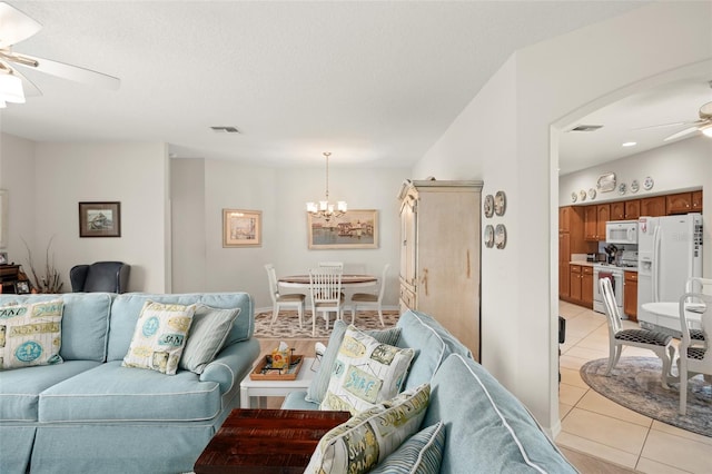 living area featuring visible vents, light tile patterned flooring, and ceiling fan with notable chandelier