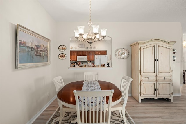 dining space with a notable chandelier, baseboards, and light wood-style floors