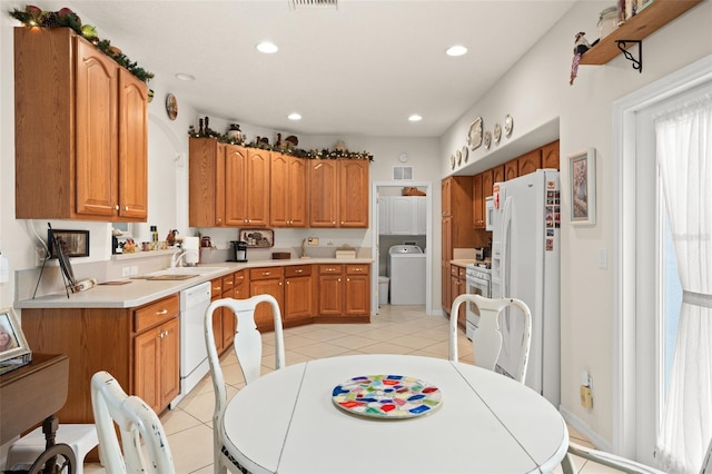 kitchen featuring white appliances, light tile patterned floors, brown cabinetry, washer / clothes dryer, and recessed lighting