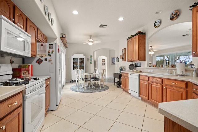 kitchen with visible vents, a sink, white appliances, arched walkways, and light countertops