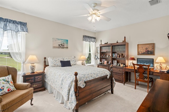 bedroom featuring light carpet, visible vents, multiple windows, and a ceiling fan