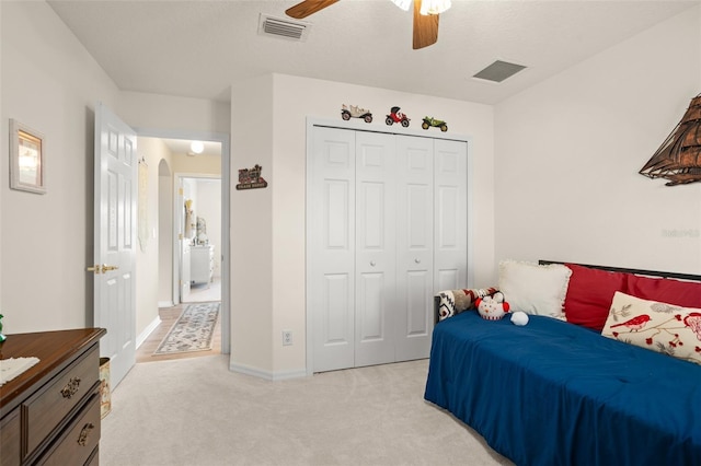 bedroom with arched walkways, visible vents, light carpet, and a closet