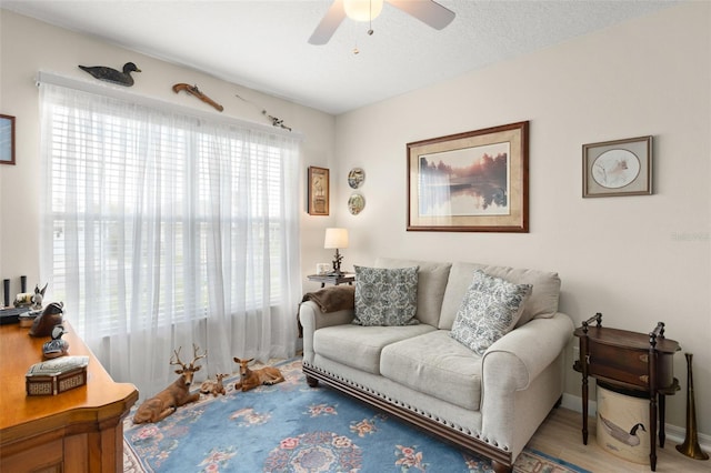 living area featuring ceiling fan, baseboards, and wood finished floors