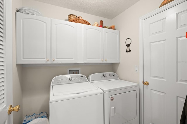 clothes washing area with a textured ceiling, cabinet space, and washer and clothes dryer