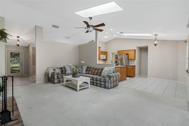 living room with light carpet, light tile patterned floors, vaulted ceiling with skylight, visible vents, and ceiling fan