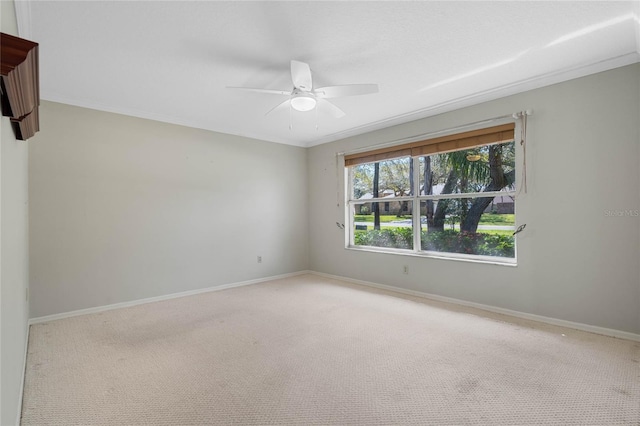 spare room featuring crown molding, carpet floors, a ceiling fan, and baseboards