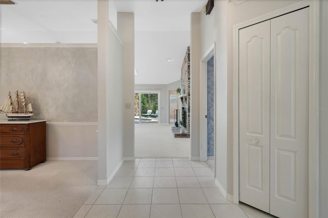 hallway with light carpet, light tile patterned floors, and baseboards