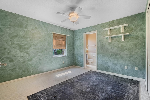 carpeted empty room featuring wallpapered walls, a textured ceiling, baseboards, and a ceiling fan