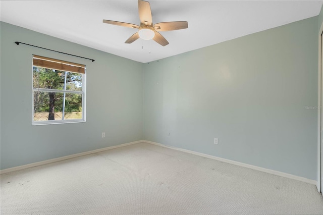 spare room with baseboards, ceiling fan, and light colored carpet