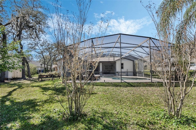 back of property featuring an outdoor pool, glass enclosure, a lawn, and a patio