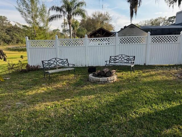 view of yard with a fire pit and fence