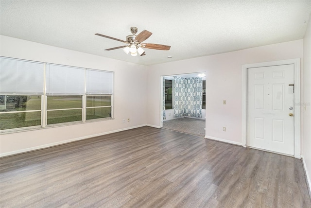 spare room with ceiling fan, a textured ceiling, baseboards, and wood finished floors