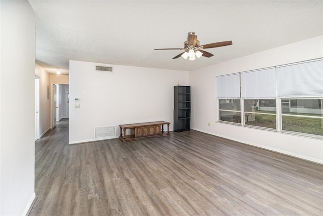 spare room featuring visible vents, a textured ceiling, baseboards, and wood finished floors