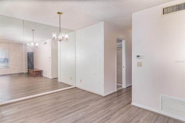 unfurnished dining area with visible vents, a textured ceiling, and wood finished floors