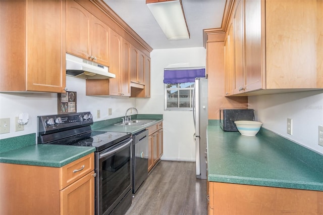 kitchen with under cabinet range hood, stainless steel appliances, wood finished floors, a sink, and dark countertops