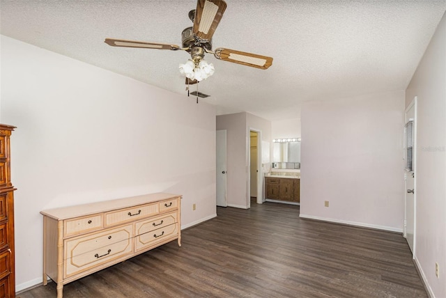 unfurnished bedroom with a textured ceiling, baseboards, and dark wood-style flooring