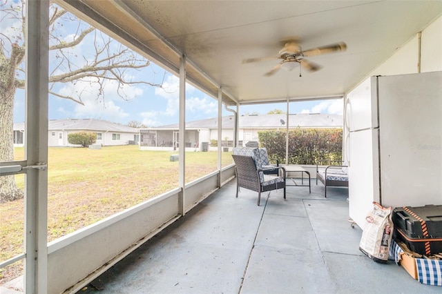 sunroom with ceiling fan and a residential view