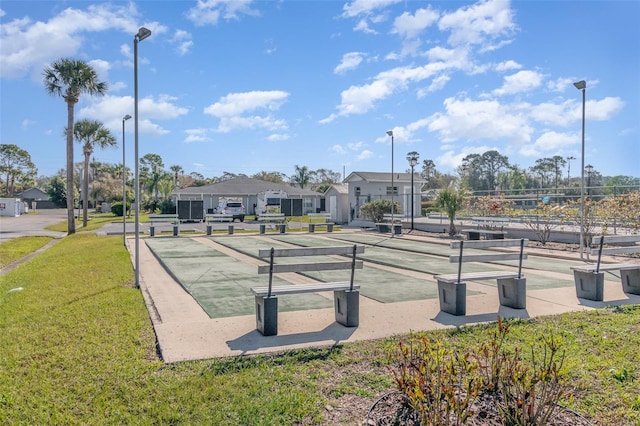 view of property's community featuring shuffleboard and a yard