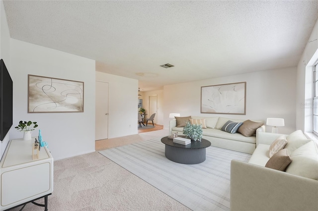 living room with carpet floors, visible vents, and a textured ceiling