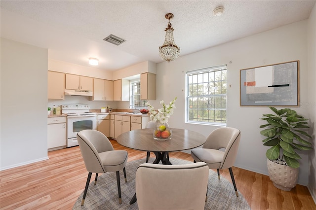 dining space featuring a textured ceiling, a notable chandelier, visible vents, baseboards, and light wood-type flooring