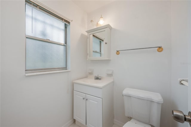 half bath featuring vanity, toilet, and baseboards