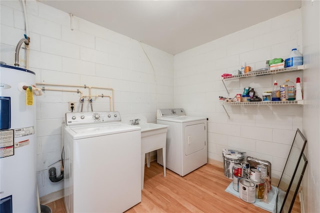 clothes washing area with laundry area, electric water heater, washer and clothes dryer, and light wood finished floors