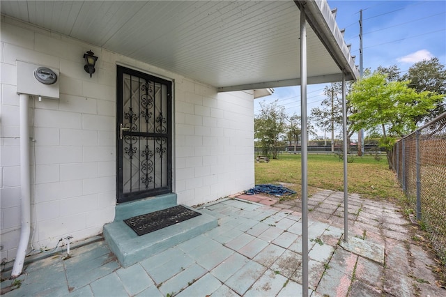 view of exterior entry with fence and concrete block siding