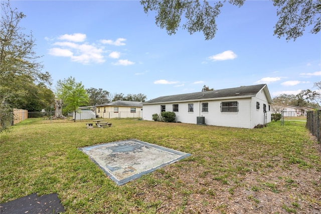 rear view of property featuring central air condition unit, a fenced backyard, and a yard