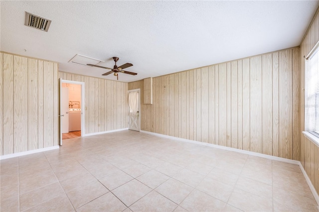 empty room with visible vents, a ceiling fan, a textured ceiling, washer / dryer, and baseboards