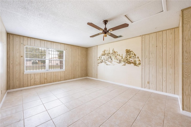 empty room featuring wooden walls, a textured ceiling, and tile patterned floors