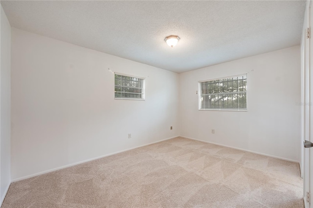 unfurnished room with light carpet, a textured ceiling, and baseboards