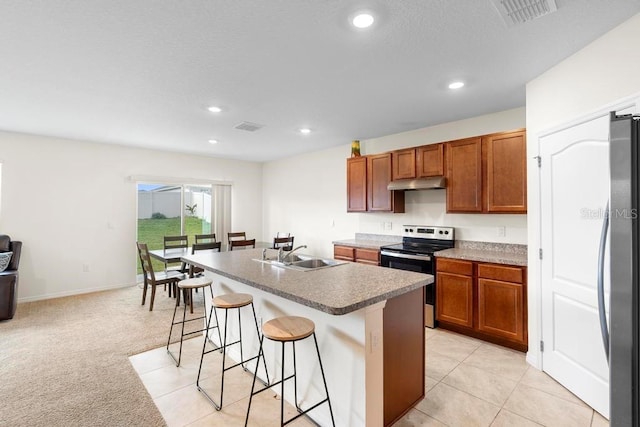 kitchen featuring under cabinet range hood, a sink, a kitchen breakfast bar, appliances with stainless steel finishes, and a center island with sink