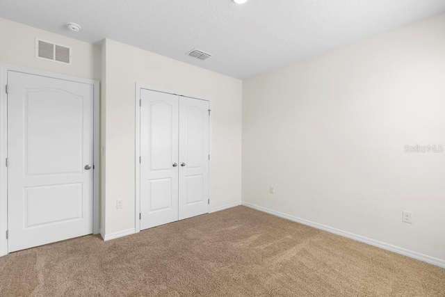 unfurnished bedroom with carpet floors, a closet, visible vents, and baseboards