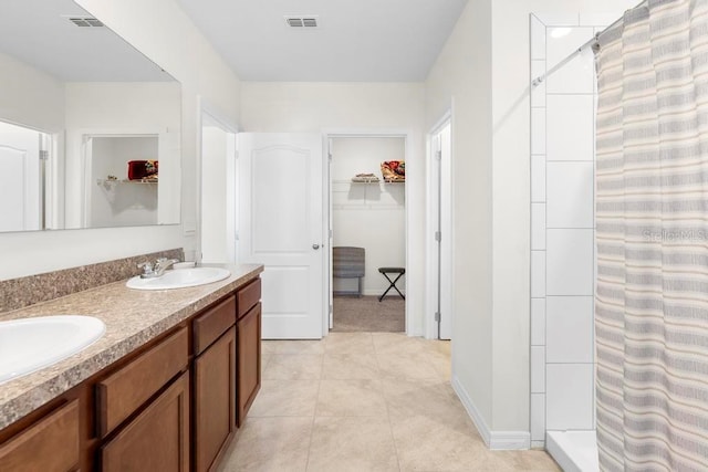 bathroom featuring a sink, a stall shower, a walk in closet, and visible vents