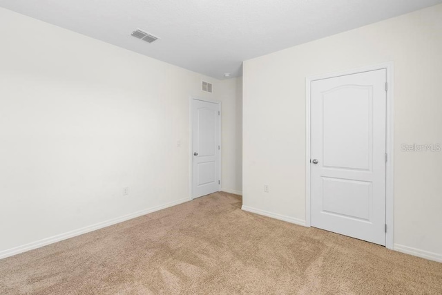 unfurnished bedroom featuring light carpet, baseboards, and visible vents