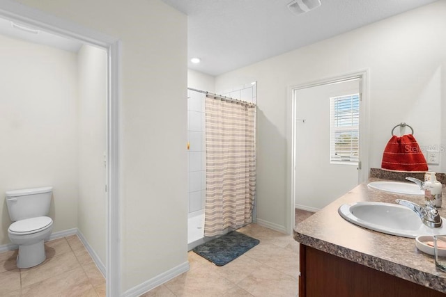 bathroom featuring double vanity, tiled shower, a sink, and visible vents