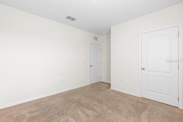 unfurnished room featuring light colored carpet, visible vents, and baseboards