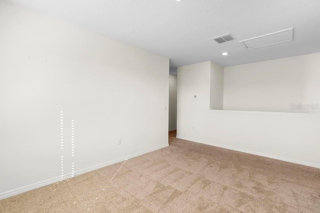 empty room with light carpet, baseboards, visible vents, and attic access