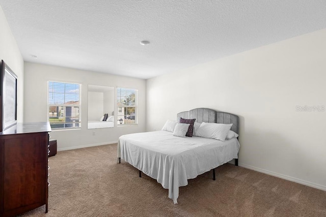 bedroom with light carpet, a textured ceiling, and baseboards