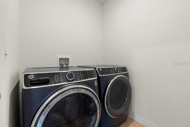 clothes washing area with laundry area, baseboards, and washer and clothes dryer