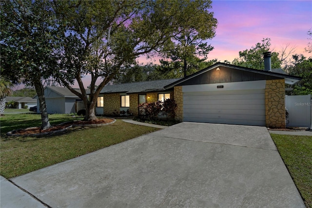 view of front of home with concrete driveway, a lawn, board and batten siding, a garage, and stone siding