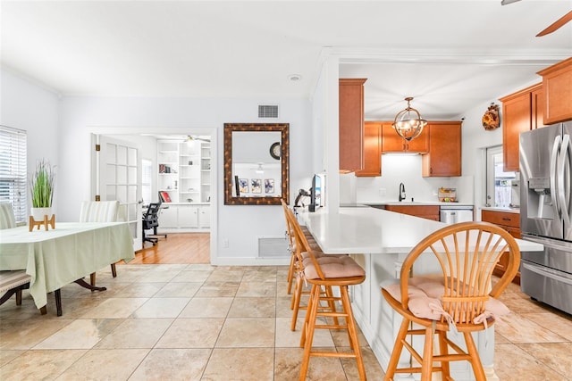 kitchen with a healthy amount of sunlight, appliances with stainless steel finishes, light countertops, and ceiling fan with notable chandelier