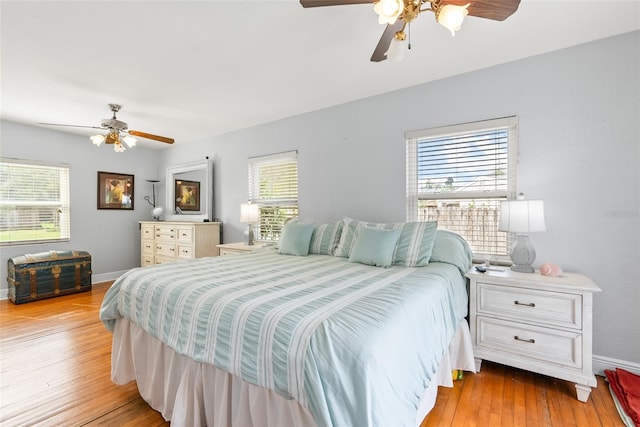 bedroom with baseboards, multiple windows, and light wood-style floors