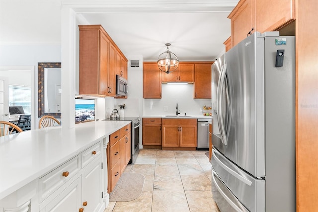 kitchen with pendant lighting, stainless steel appliances, light countertops, brown cabinetry, and a sink