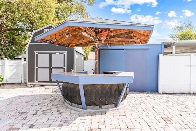 view of patio / terrace featuring an outbuilding, fence, a gazebo, and a storage unit