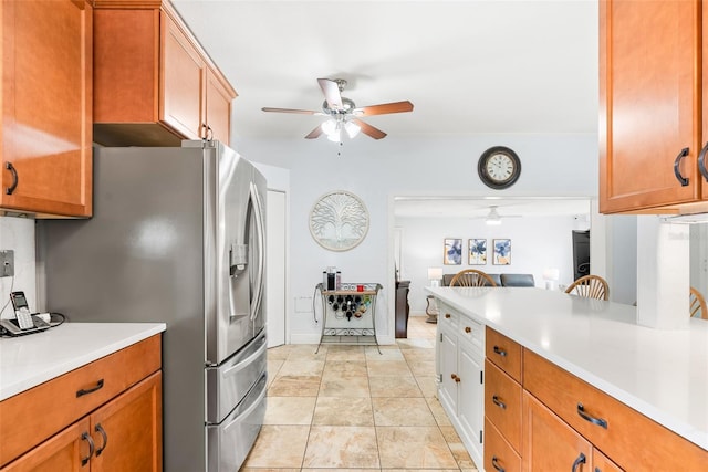 kitchen featuring brown cabinetry, stainless steel fridge, light countertops, and a ceiling fan