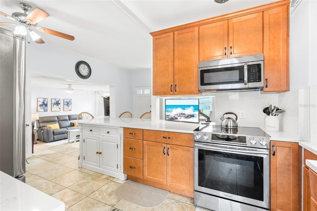 kitchen featuring brown cabinets, a ceiling fan, stainless steel appliances, and light countertops